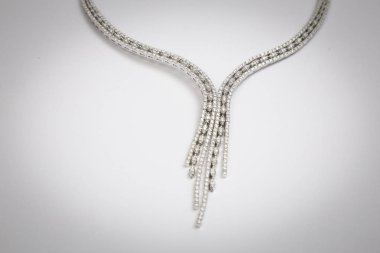 beyaz zemin üzerine gümüş kolye.