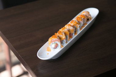 Somon, avokado, somon yumurtası ve baharatlı krema sosuyla doldurulmuş California somonlu suşi ruloları. Japon yemek tarzı.