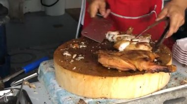 Şefin elinde bıçak, maşa ve kızarmış tavuk eti parçaları var. Yazın yerel gıda pazarında. Yakın görüş. Açık hava yemekleri, gastronomi, aşçılık, sokak yemekleri konsepti.