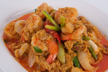 Masada beyaz tabakta köri tozu ile kızarmış karidesi karıştır