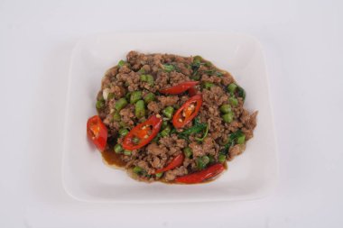 Kızarmış domuz kıyması ve beyaz tabakta fesleğen.