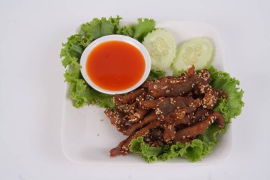 Kızarmış biftek dilimi ve beyaz arka planda lezzetli bir tat veren otlar.