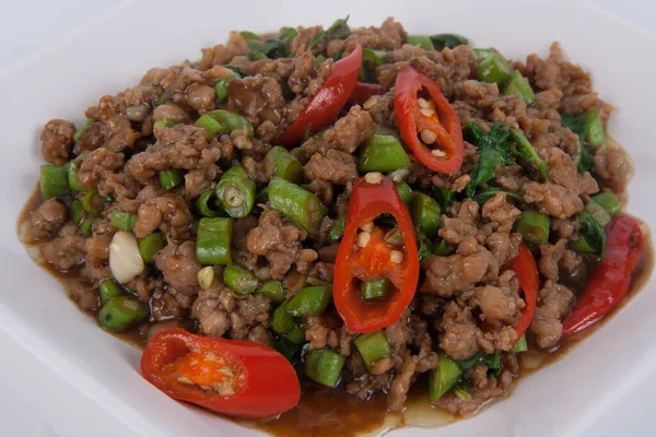 Kızarmış domuz kıyması ve beyaz tabakta fesleğen.