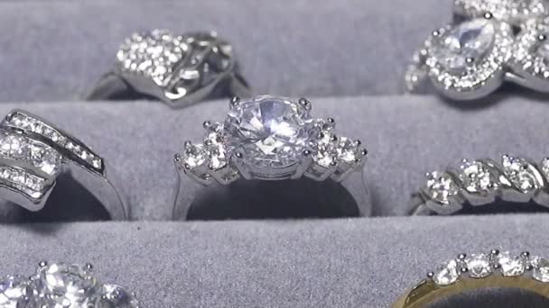 Tiro de perto de um anel com um diamante na exposição da loja de jóias. Muitos anéis de noivado com pedras preciosas e câmera está ampliando para o anel com o diamante. — Vídeo de Stock