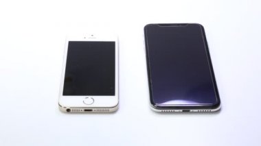 BANGKOK, THAILAND - 9 OCT 2020: Eski tip iPhone 5 ile beyaz arka plandaki iPhone X akıllı telefonu karşılaştıran adam portresi - eski vs modern telefon