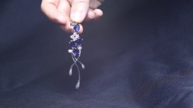 Küçük elmaslı iki altın safir küpe. Mavi saten arka planda safir değerli taşlı bir çift platin küpe. Lüks kadın mücevherleri, yakın plan.