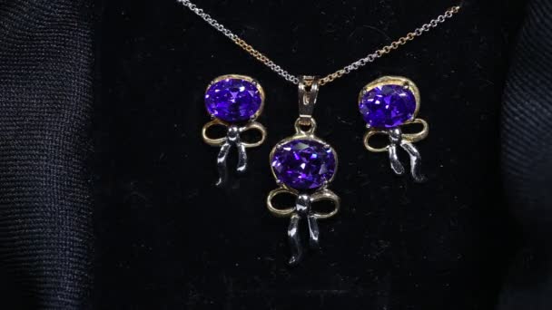 Zestaw biżuterii zawierający naszyjnik, prezentowany złoty łańcuszek z ametystem fioletowy na złotym wisiorku oraz komplet kolczyków — Wideo stockowe