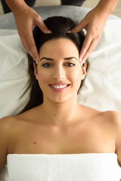 Top view of young caucasian smiling woman receiving a head massage in a spa center. Female patient is receiving treatment by professional therapist.
