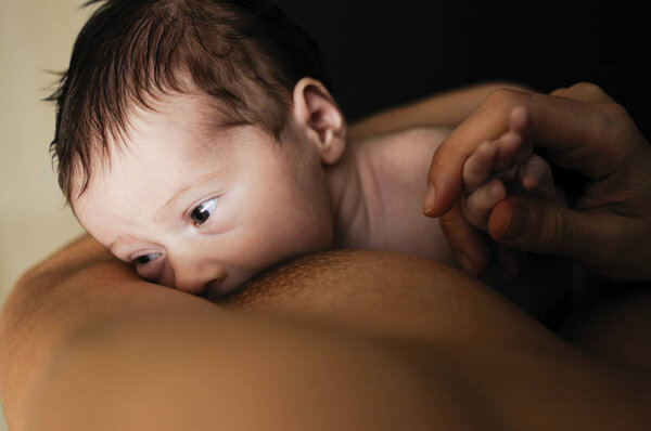 Young mother breastfeeding newborn baby at home