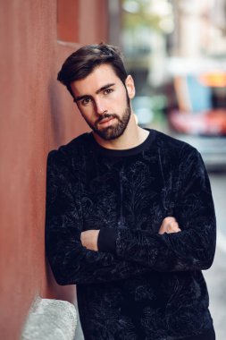 Genç kamera rahat kıyafetler giymiş kentsel arka planda bakarak adam, moda, model sakallı. Adam sokakta modern saç ve sakal ile.