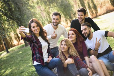 Kent parkta selfie alarak arkadaş grubu. Beş genç insanlar rahat kıyafetler giyen.
