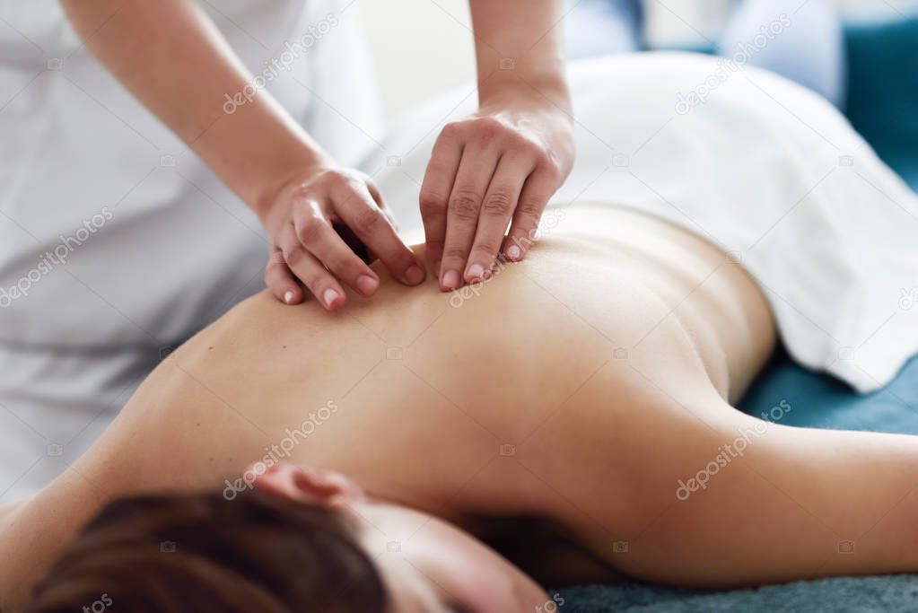 Young woman receiving a back massage by professional therapist. Female patient is receiving treatment in a spa center. 