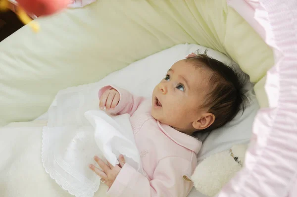 两个月大的女婴看着婴儿床上的娃娃 — 图库照片