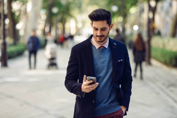 在街上有魅力的男人穿着英国优雅的西装 手里拿着智能手机 城市背景下的现代发型的年轻大胡子商人 — 图库照片