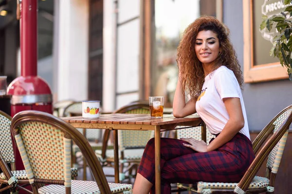 年轻的阿拉伯妇女微笑着 坐在街道上的一个城市酒吧 阿拉伯女孩在休闲的衣服喝苏打户外 — 图库照片