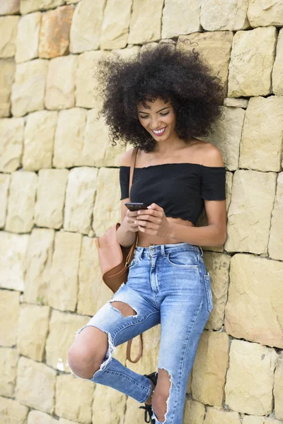 Glimlachend Zwarte Vrouw Met Krullend Haar Haar Slimme Telefoon Buitenshuis — Stockfoto