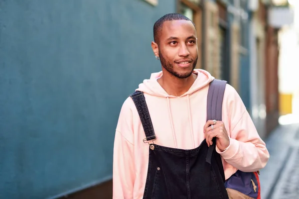 Mladý černý muž chodící usmívající se po ulici. — Stock fotografie