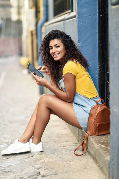 Mujer árabe feliz sentado en el paso urbano con una tableta digital —  Fotos de Stock