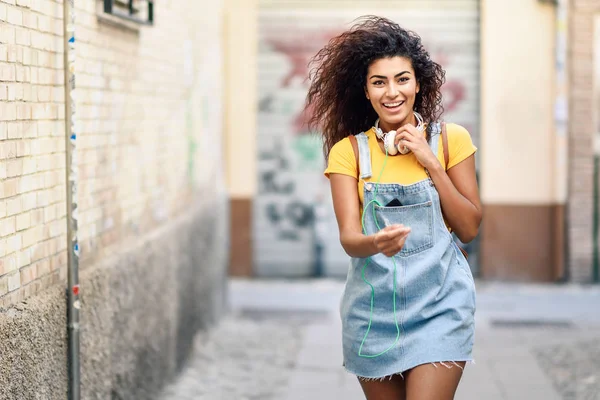 Jonge Afrikaanse vrouw met hoofdtelefoon buiten wandelen — Stockfoto