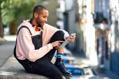Genç siyah adam kentsel arka planda dijital tablet kullanma.
