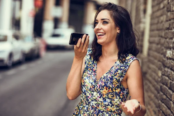 Улыбающаяся молодая женщина записывает голосовую запись в свой смартфон — стоковое фото