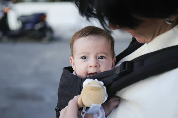 Mother carrying her baby girl in a baby carrier — Stock Photo, Image