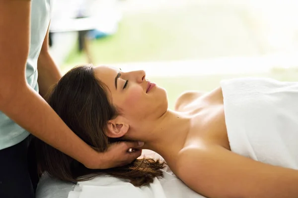 Jovem sorrindo mulher recebendo uma massagem na cabeça em um centro de spa . — Fotografia de Stock