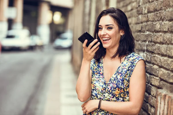 Uśmiechnięta młoda kobieta nagrywania notatki głosowej w jej silny telefon — Zdjęcie stockowe