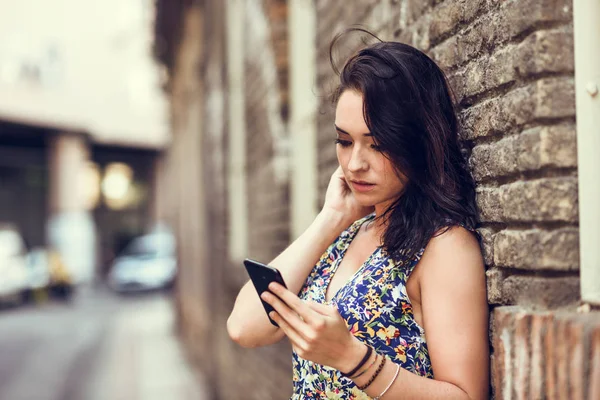 Σοβαρή νεαρή γυναίκα χρησιμοποιώντας το έξυπνο τηλέφωνο της σε εξωτερικούς χώρους. — Φωτογραφία Αρχείου