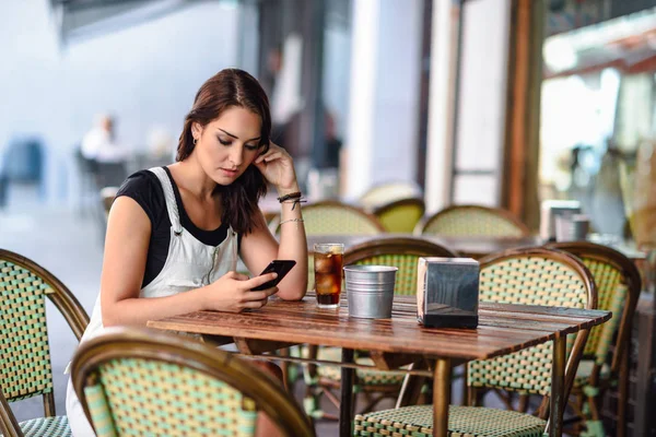 Chica con ojos azules sentado en la cafetería urbana utilizando el teléfono inteligente —  Fotos de Stock