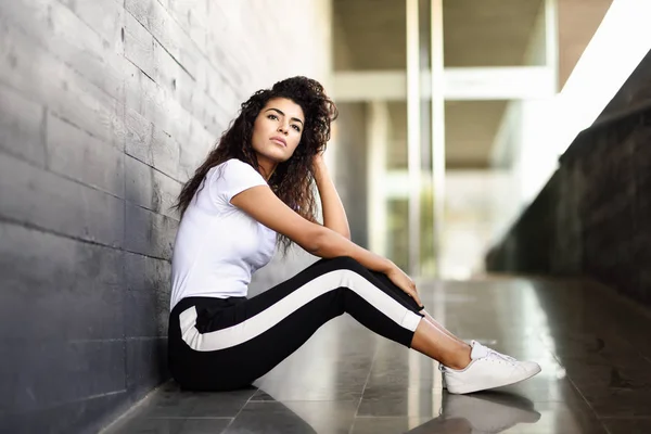 African woman with black curly hairstyle sitting on urban floor. — Stock Photo, Image