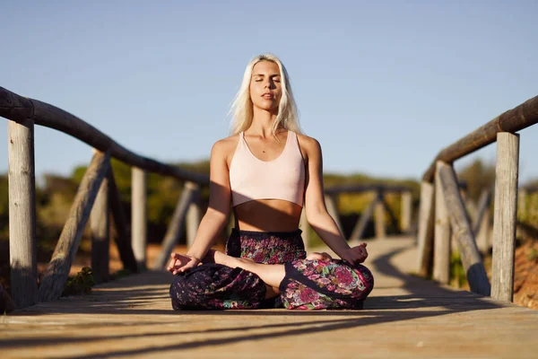 Kaukasierin praktiziert Yoga auf Holzbrücke. — Stockfoto