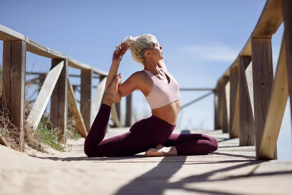 Mujer rubia caucásica practicando yoga en la playa — Foto de Stock