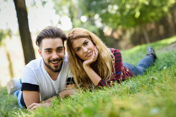 Güzel genç bir çift bir kentsel Park çimenlerin üzerinde döşeme. — Stok fotoğraf