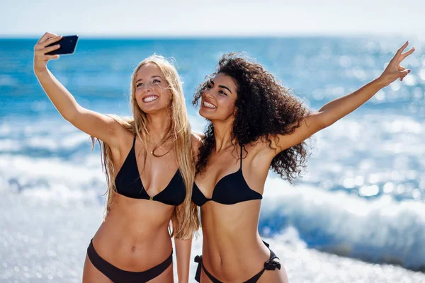 Duas mulheres tirando fotos selfie com smartphone na praia — Fotografia de Stock