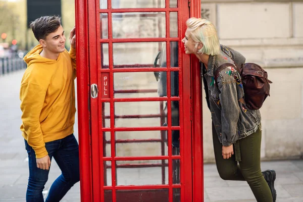 Jeune couple d'amis près d'une cabine téléphonique rouge britannique classique — Photo