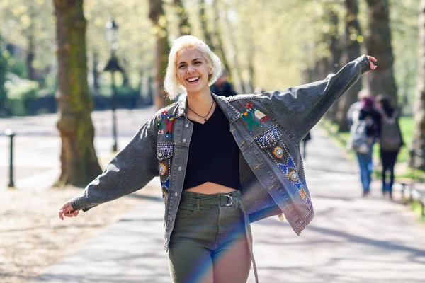 Brazos de mujer joven levantados disfrutando del aire fresco en el verde parque urbano . — Foto de Stock