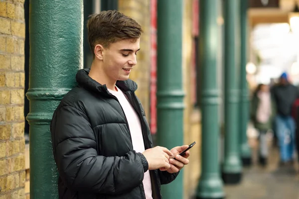 Joven hombre urbano usando teléfono inteligente en el fondo urbano . — Foto de Stock