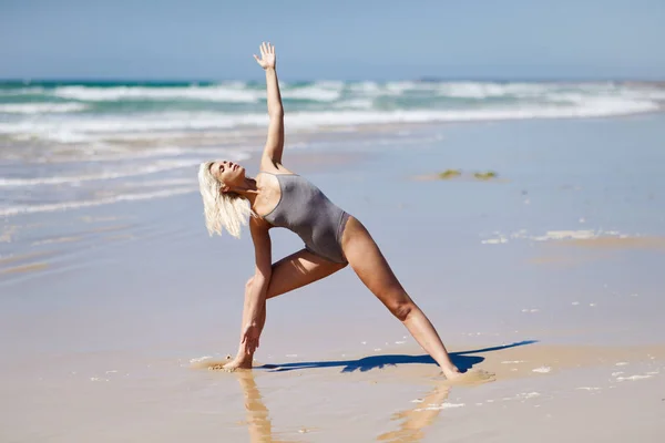 Kaukasisch blonde vrouw het beoefenen van yoga in het strand — Stockfoto