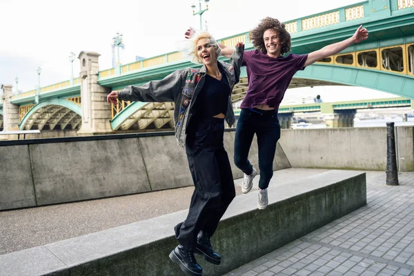 Funny couple junping near the Southwark bridge over River Thames, London — Stock Photo, Image