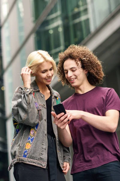 Pareja feliz usando teléfono inteligente en el fondo urbano . —  Fotos de Stock