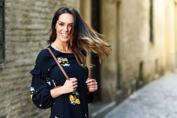 Mujer joven moviendo su pelo largo en el fondo urbano . — Foto de Stock