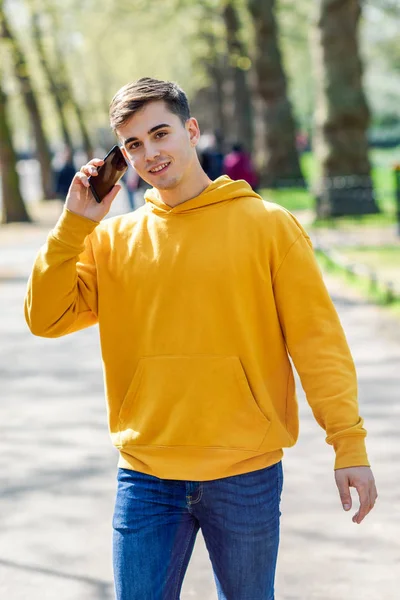 Молодой городской человек с помощью смартфона гуляет по улице в городском парке в Лондоне . — стоковое фото