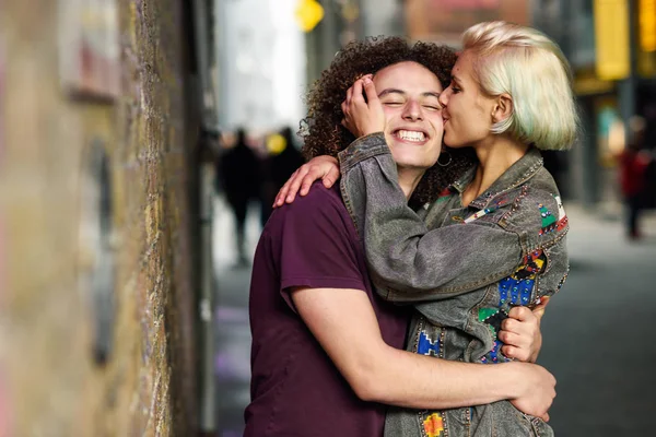 Young woman kissing her boyfriend in urban background on a typical London street — Stock Photo, Image