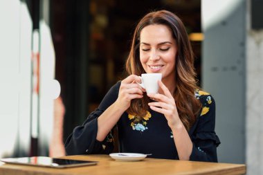 Orta yaşlı bir kadın bir şehir kafe barda kahve içiyor.