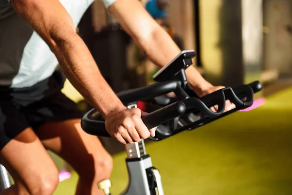 Hände eines Mannes, der in einem Fitnessstudio beim Cyclo Indoor trainiert. — Stockfoto