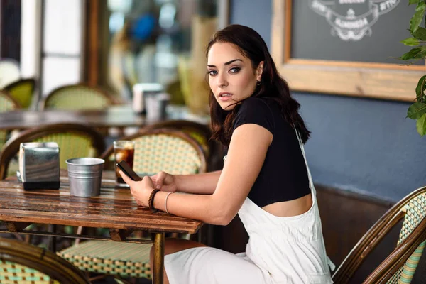 Meisje met blauwe ogen, zittend op stedelijke café met behulp van slimme telefoon — Stockfoto