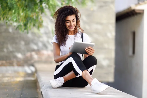 Joven mujer negra en ropa deportiva usando tableta digital al aire libre —  Fotos de Stock