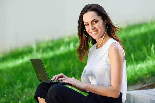 Mujer joven trabajando con su computadora portátil sentada en el suelo . —  Fotos de Stock