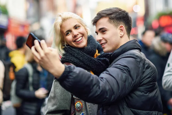 Glückliches Touristenpaar macht Selfie in einer belebten Straße. — Stockfoto